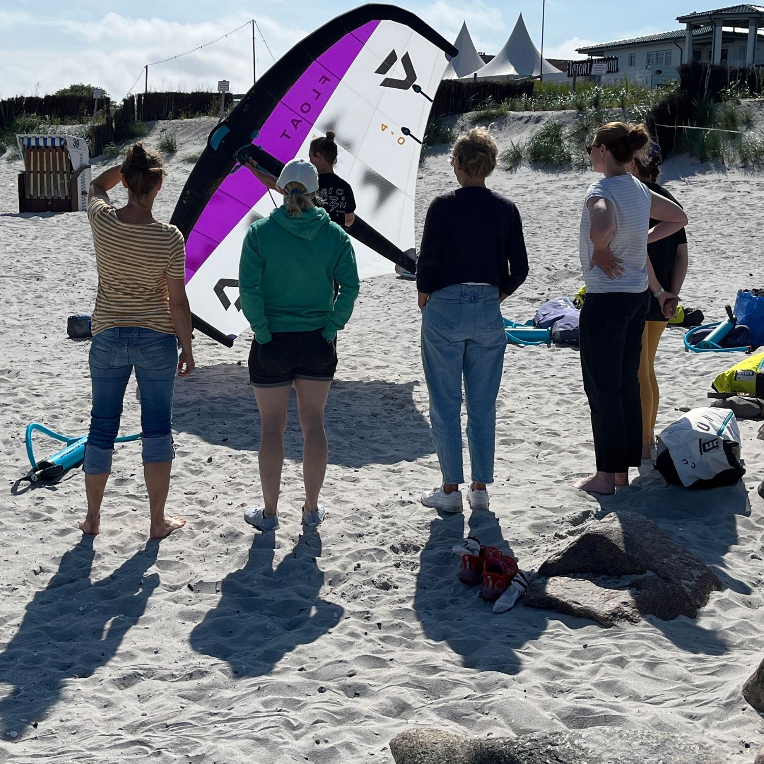 Group of people at the beach preparing a kite.