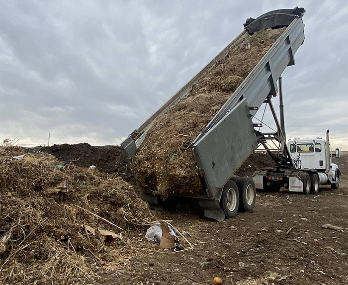 A large truck dumping a load of yard wasted at a commercial composting facility