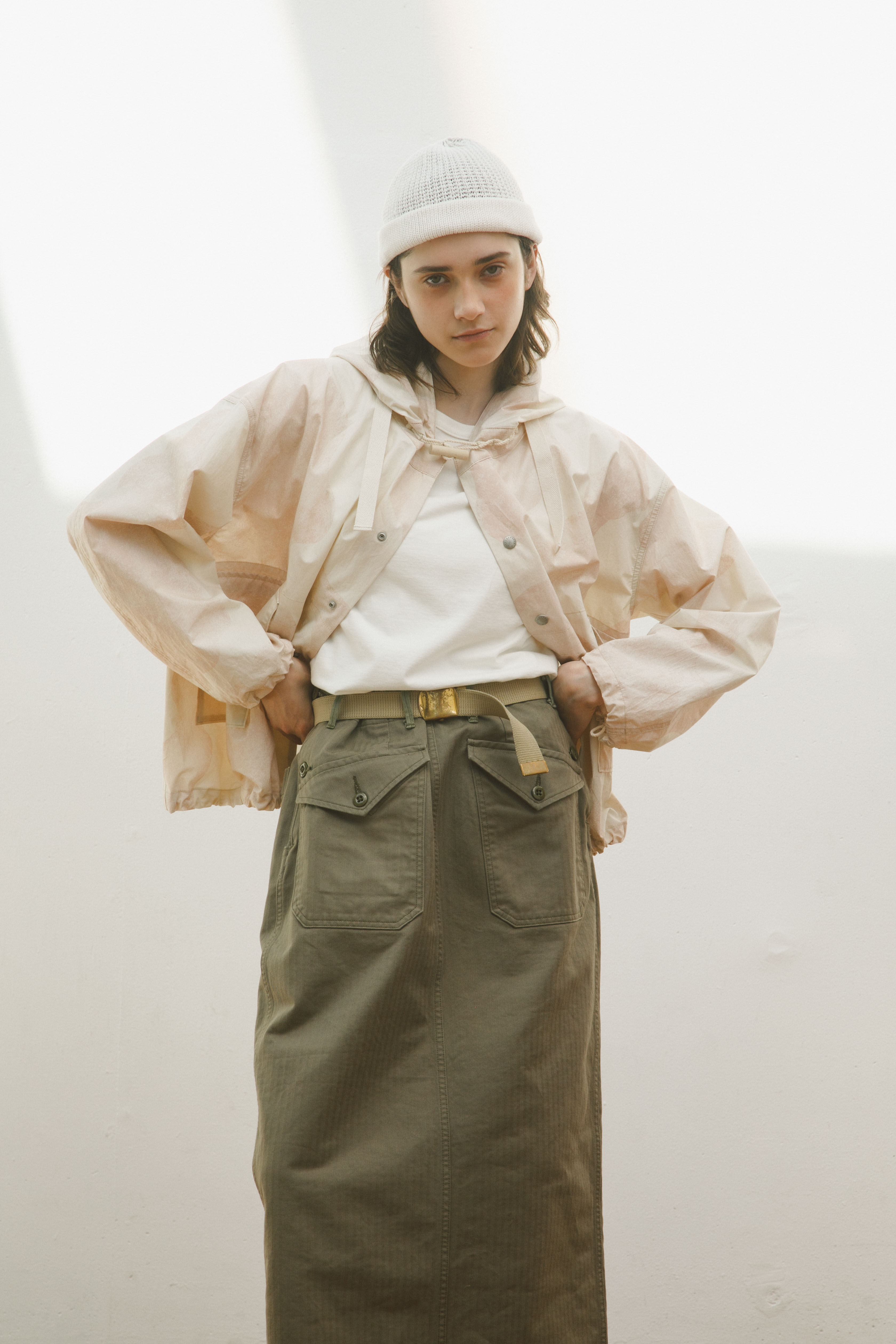 Person wearing a light jacket, white shirt, and long skirt, posing confidently.