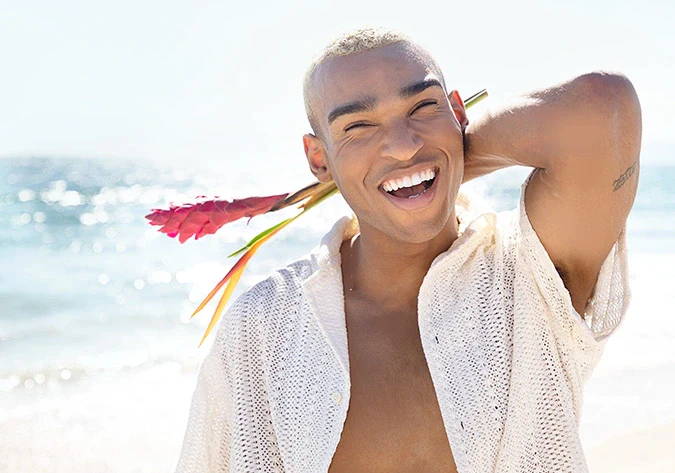 Man on a beach smiling with flowers