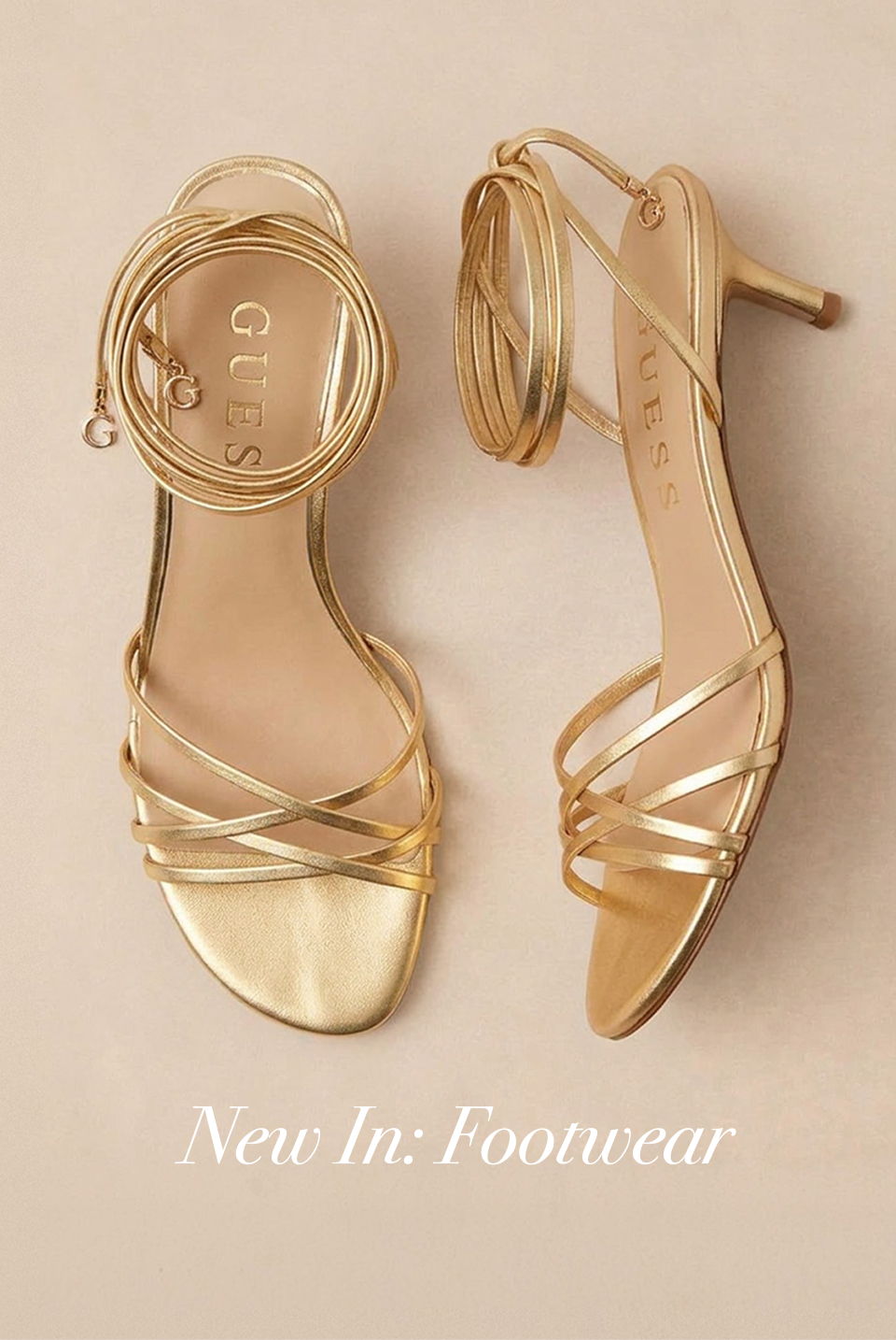 Gold strappy high-heeled sandals on a beige background.