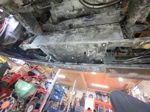 Underside view of protective skid plate bolted to vehicle chassis in garage