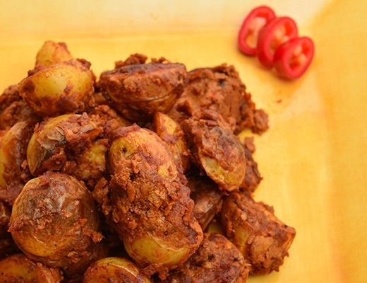 A plate of spiced potatoes garnished with red chili slices.