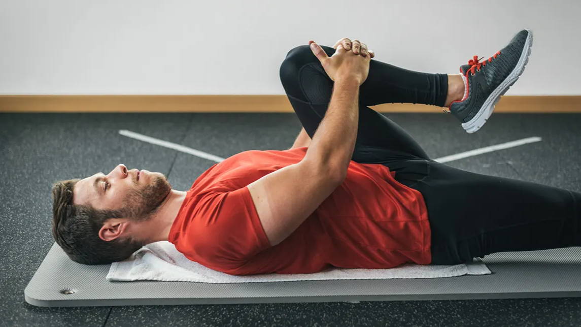 Man stretching while laying on workout mat