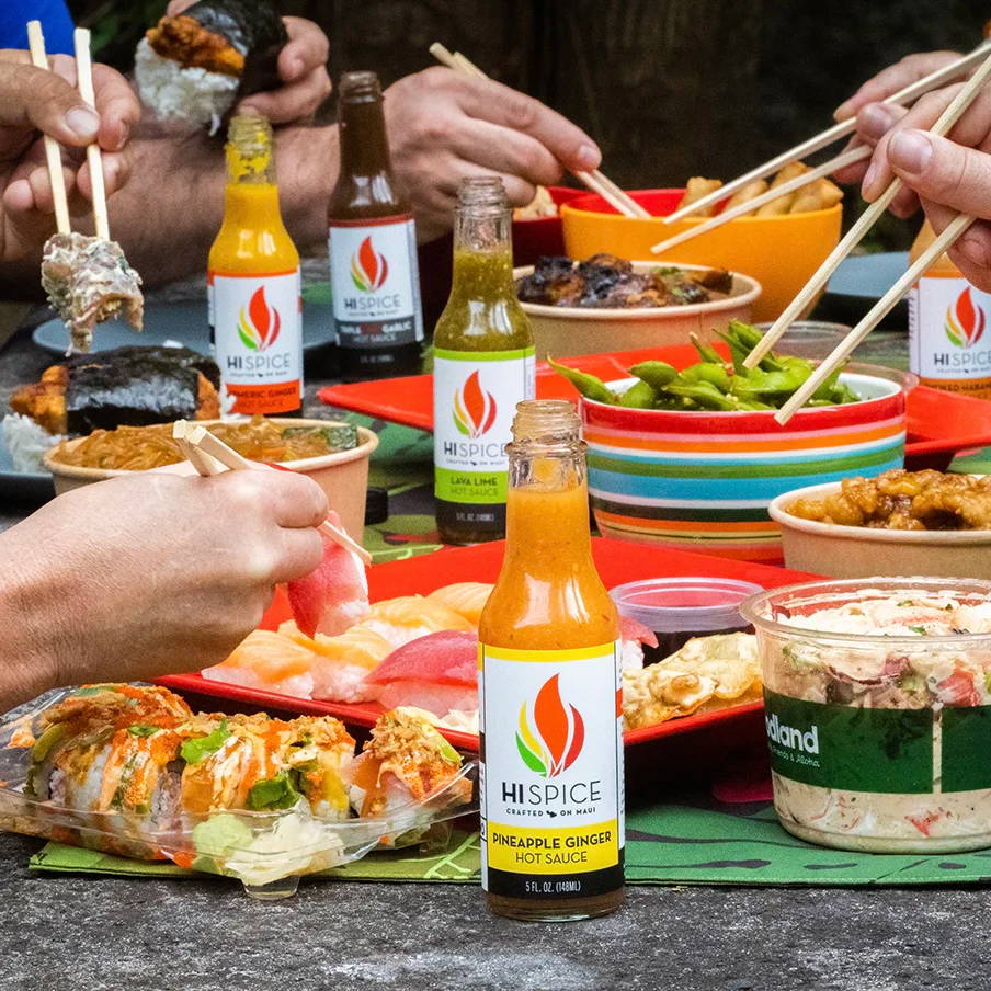 A table filled with food and drinks, hands using chopsticks.