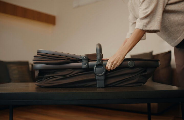 A person collapsing a iCandy Peach 8 stroller on a table.