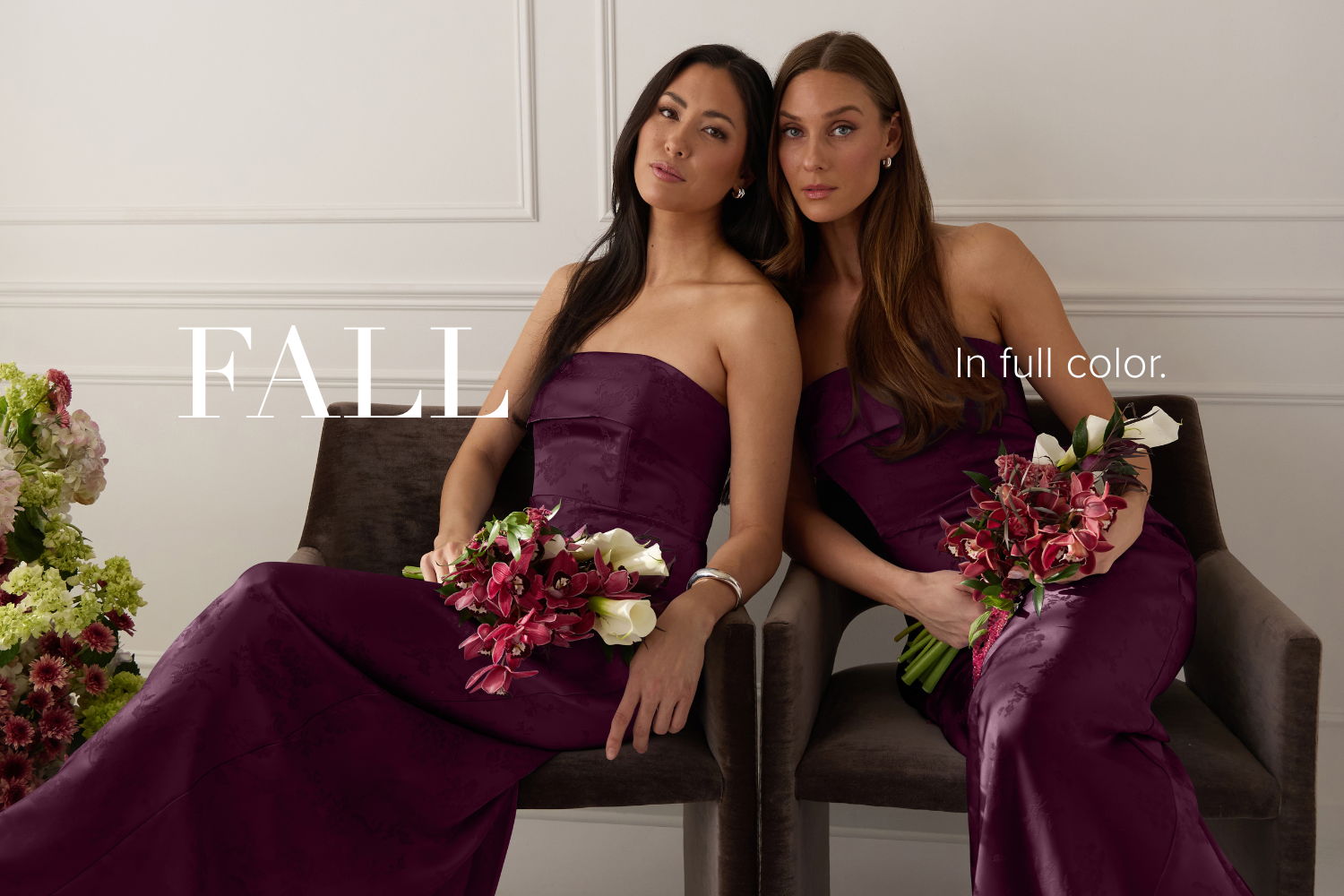 Two women in purple dresses holding floral bouquets, posed together.