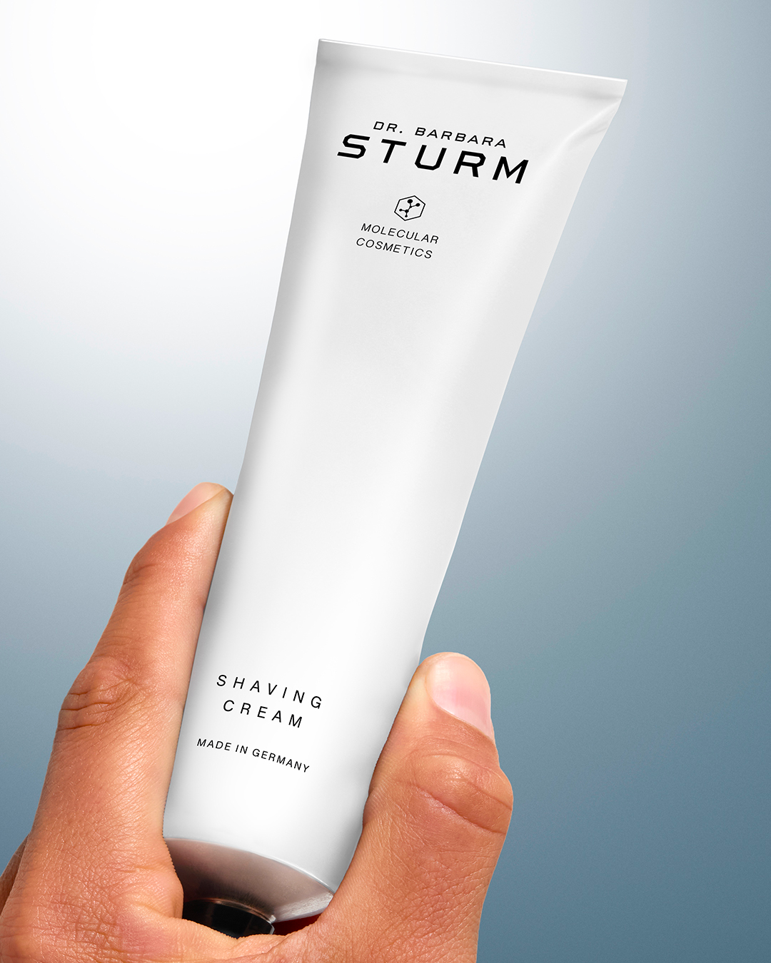 Hand holding a tube of Dr. Barbara Sturm shaving cream.