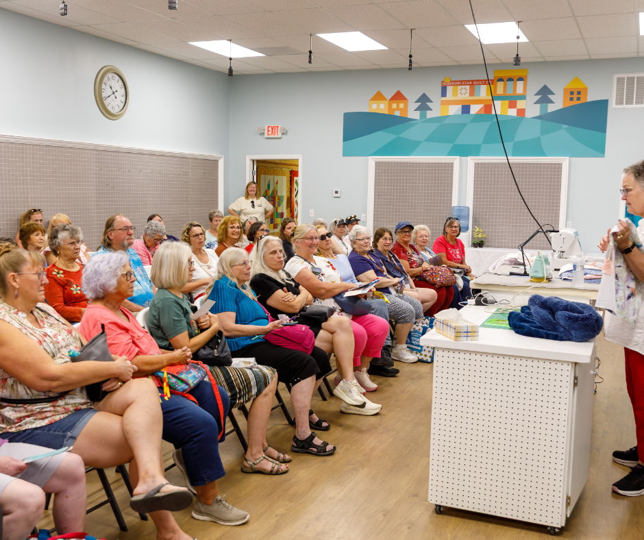 A group of people seated in a community room listening to a speaker.