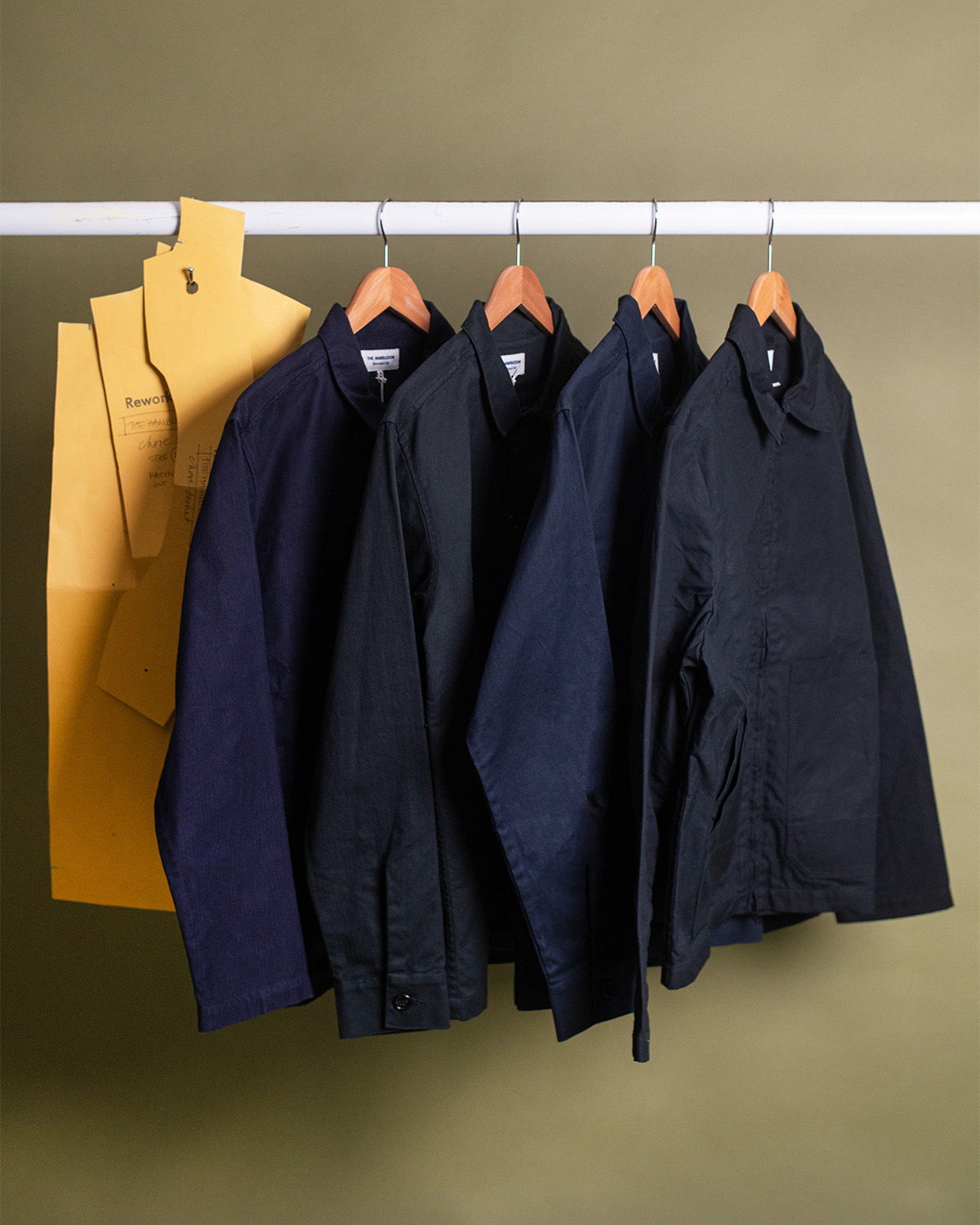 Four jackets hanging on a rack with yellow garment tags.