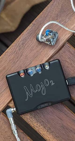 A Mojo 2 audio device on a wooden surface with earphones.