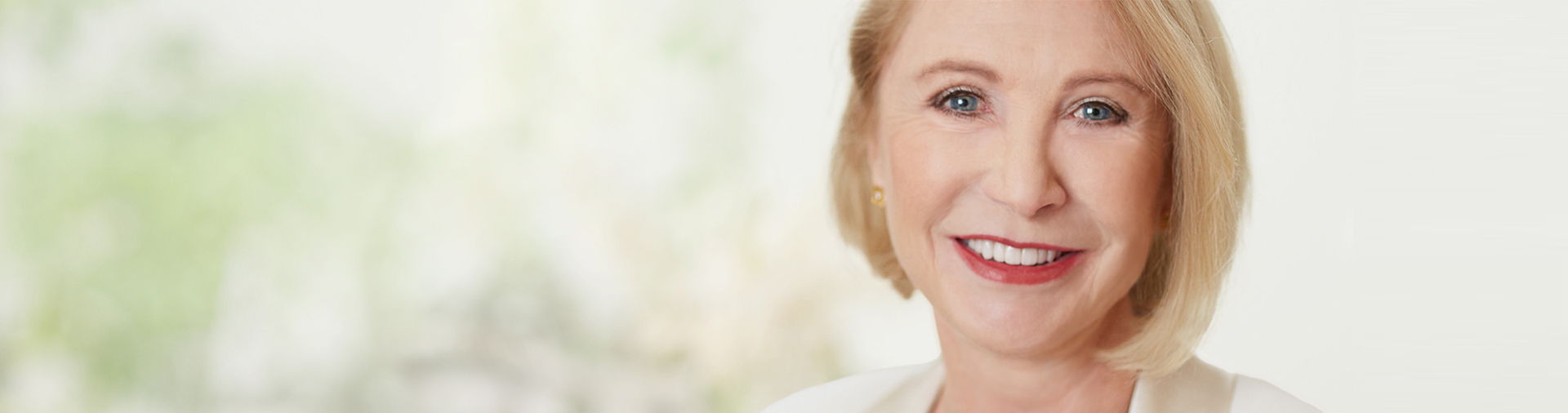 Smiling woman with short blonde hair, bright background.