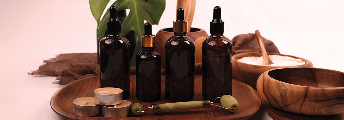 Bottles of essential oils arranged on a wooden tray with natural elements.