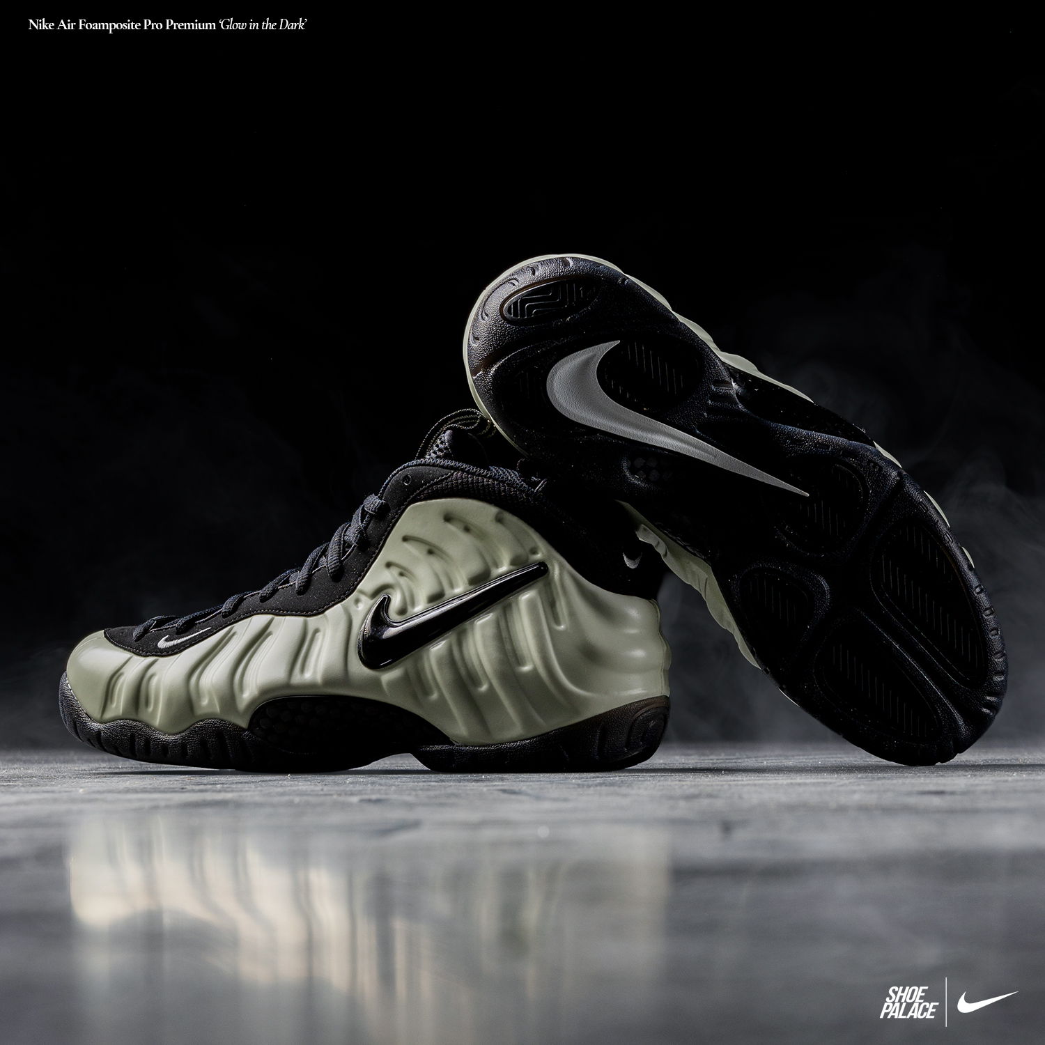 Nike Foamposite sneakers in black and light green on a reflective surface.