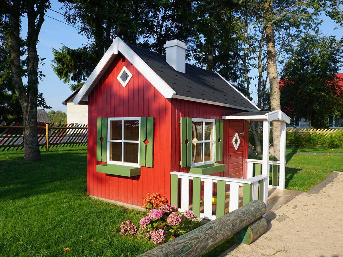 Red wooden DIY playhouse with green flower boxes and wooden porch by WholeWoodPlayhouses