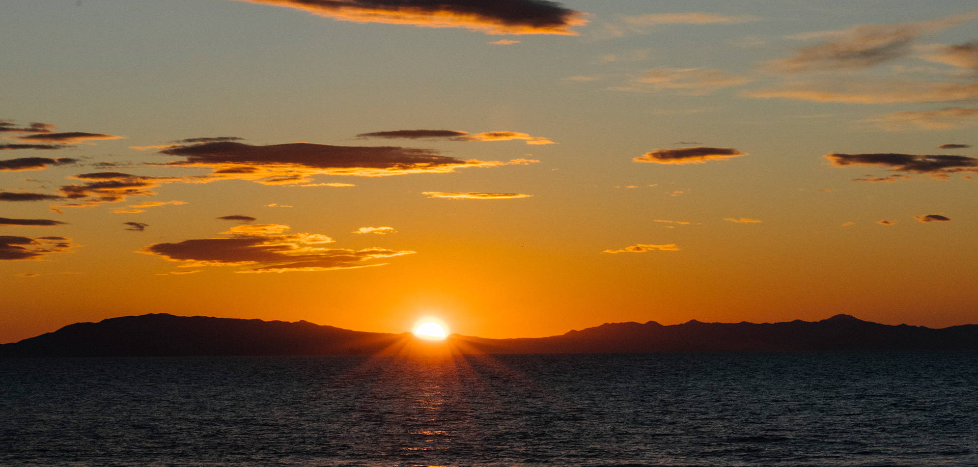 An orange sunset fading into the horizon over the mountains Rumpl blanket sunset fade