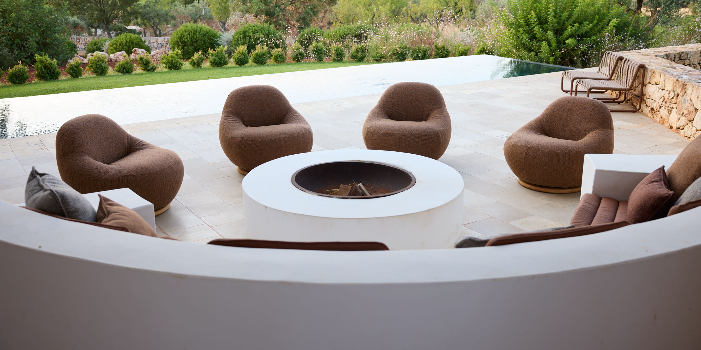 Plush brown rounded modern chairs around a white circular fire pit