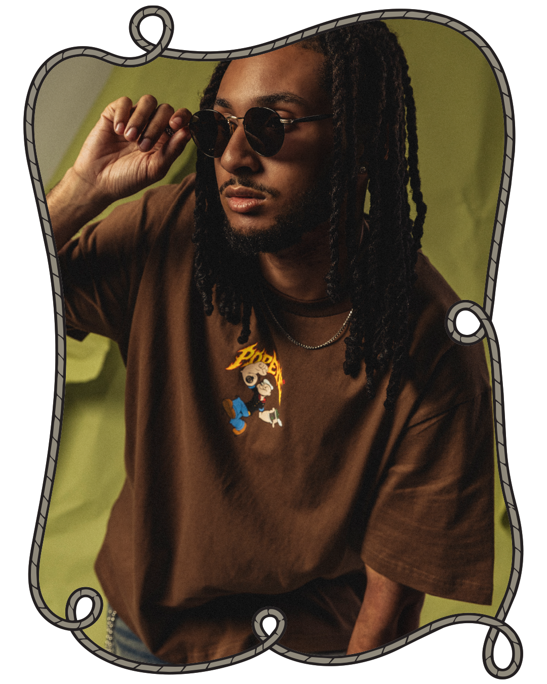 Person wearing sunglasses and a graphic t-shirt against a green background.