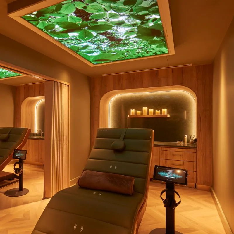 A serene spa room with a green leaf ceiling and comfortable reclining chair.