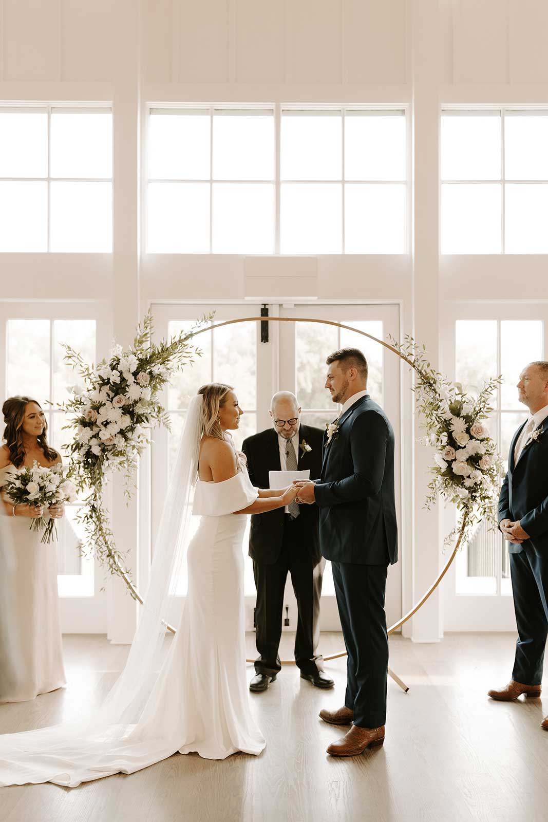 Bride and groom in front of circle shaped arbor