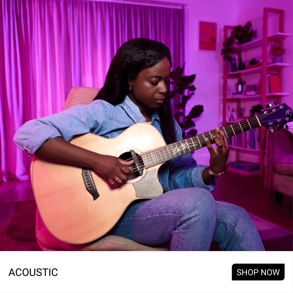 Person playing an acoustic guitar in a softly lit room.