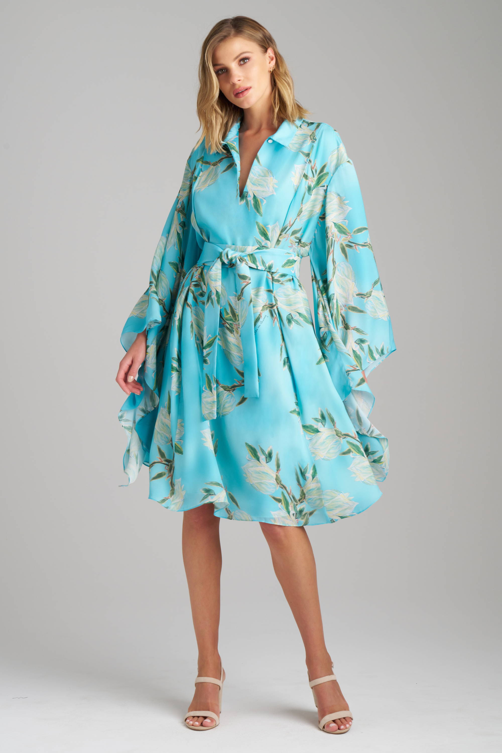 Woman wearing blue short silk dress in a floral print with kimono sleeves and self tie belt for a destination wedding 