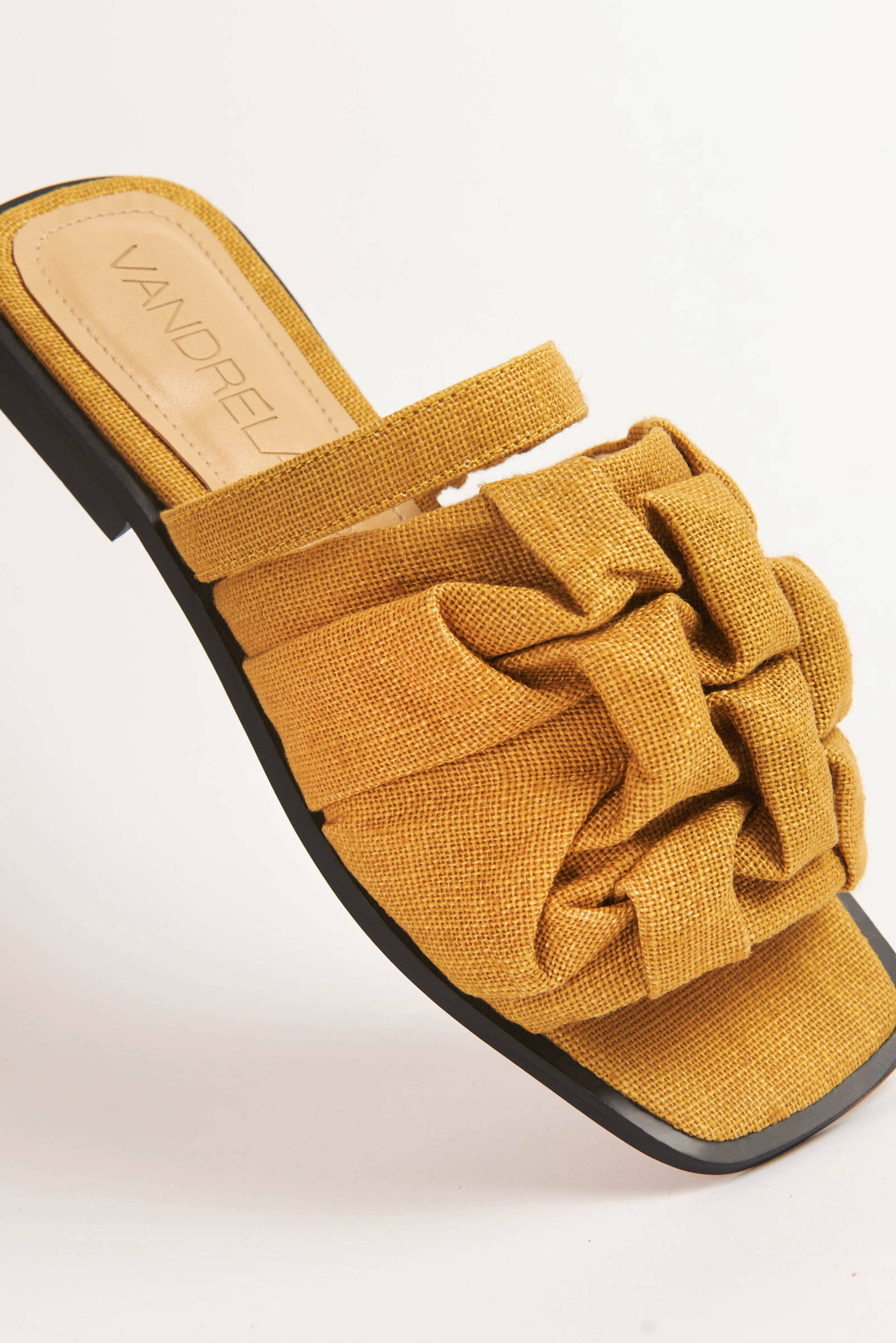 Closeup of Vandrelaar vegan Simone sandal in vibrant mustard yellow linen featuring canadian smocking detailing