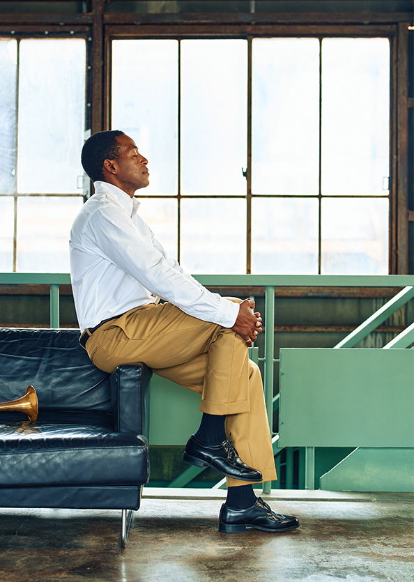Man sitting on a couch, gazing thoughtfully out of a window.