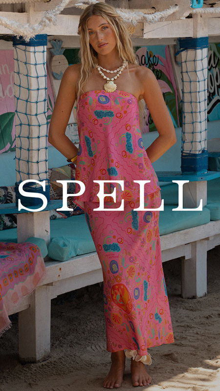 Woman in a colorful dress standing in a beachside setting.
