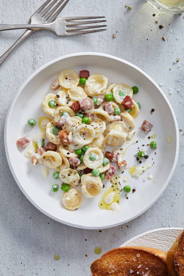 Creamy pasta with pancetta and peas served with crispy bread