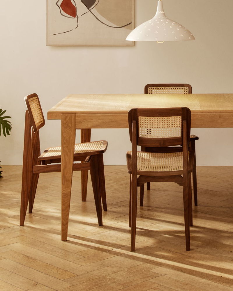 A wooden S-Table dining table with four chairs in a well-lit room.