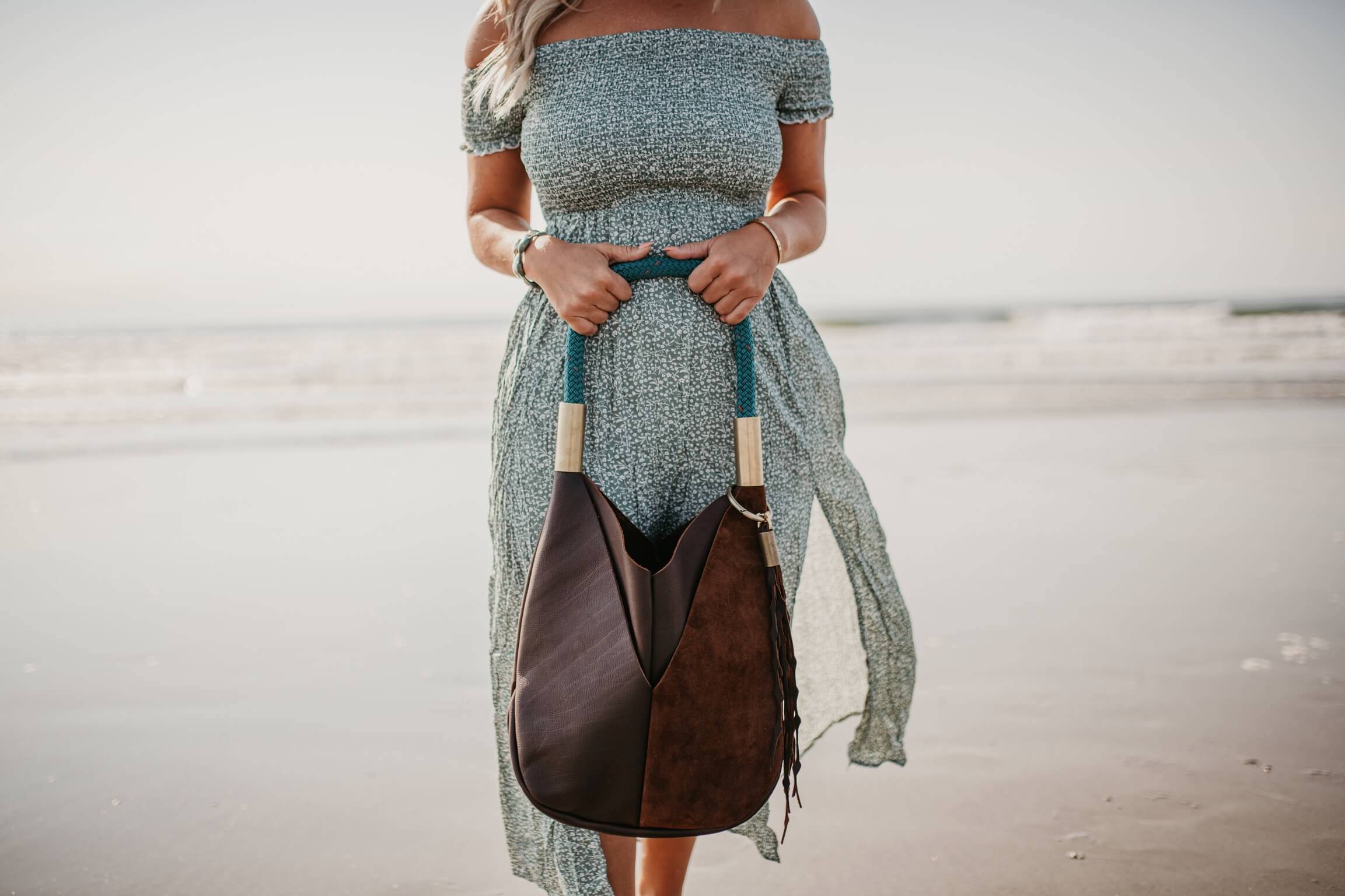 woman holding brown leather totebag on the beach