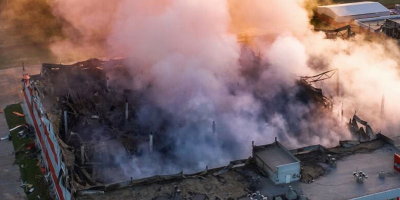 Aerial view of a building engulfed in smoke and fire.