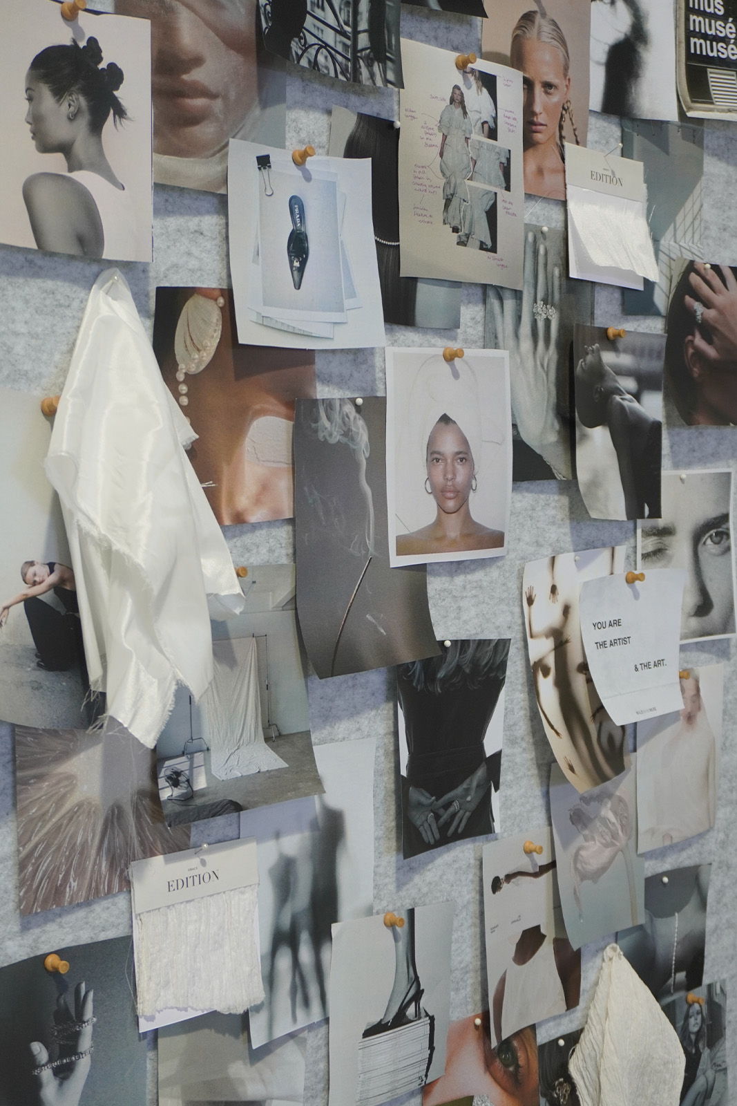 A collage of various black and white photographs pinned to a wall.