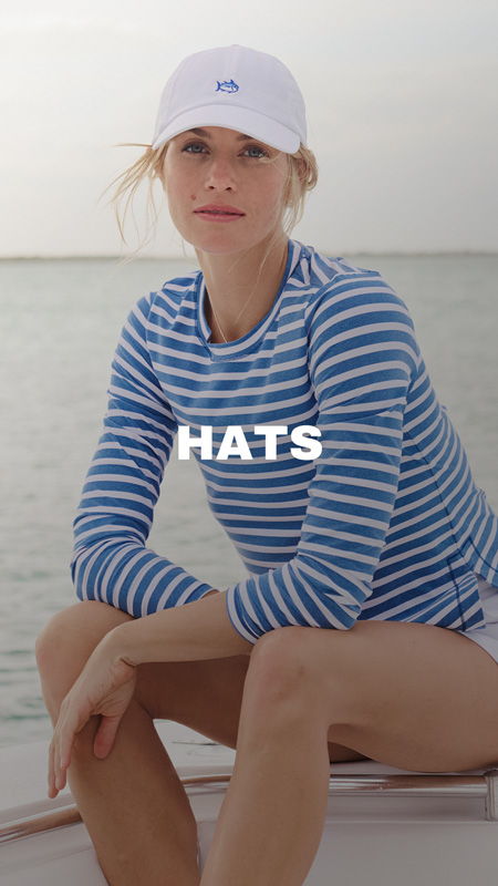 A woman in a striped shirt wearing a white hat on a boat.