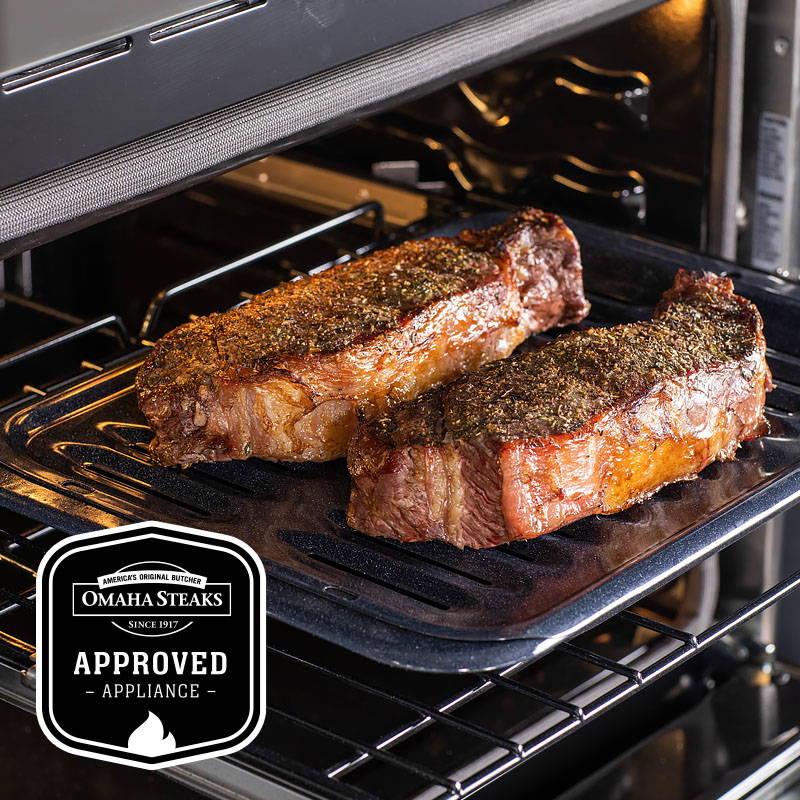 Two delicious New York Strip steaks on a broiler pan in a GE Oven. Omaha Steaks Approved Appliance.