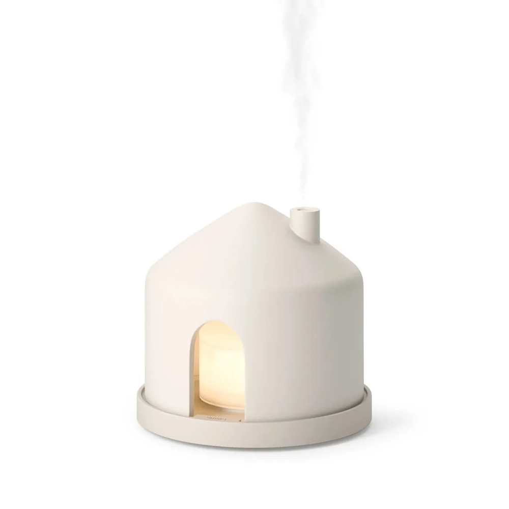 A small white ceramic house emitting steam from its chimney.