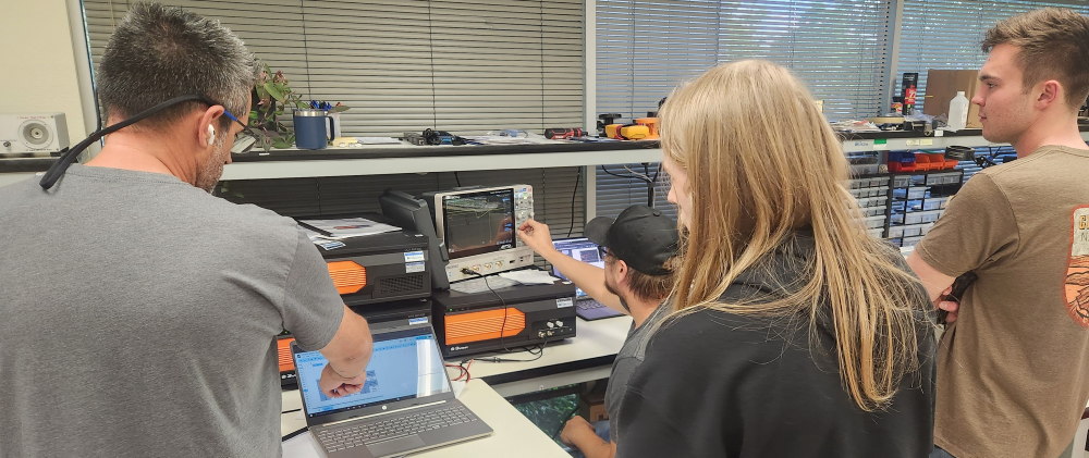 People collaborating at workstations with laptops and equipment.