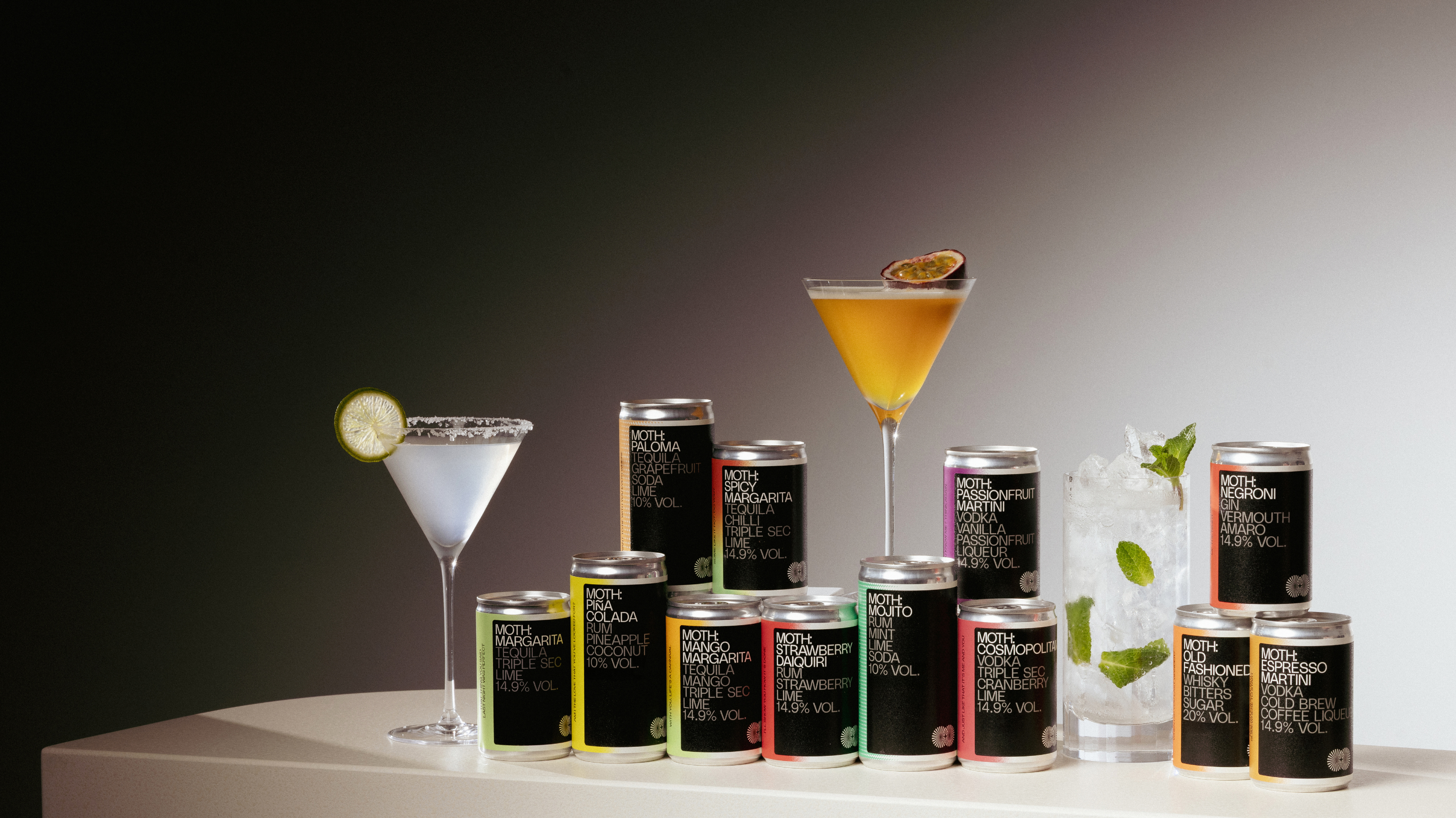 Cans of beverages displayed with cocktails on a table.