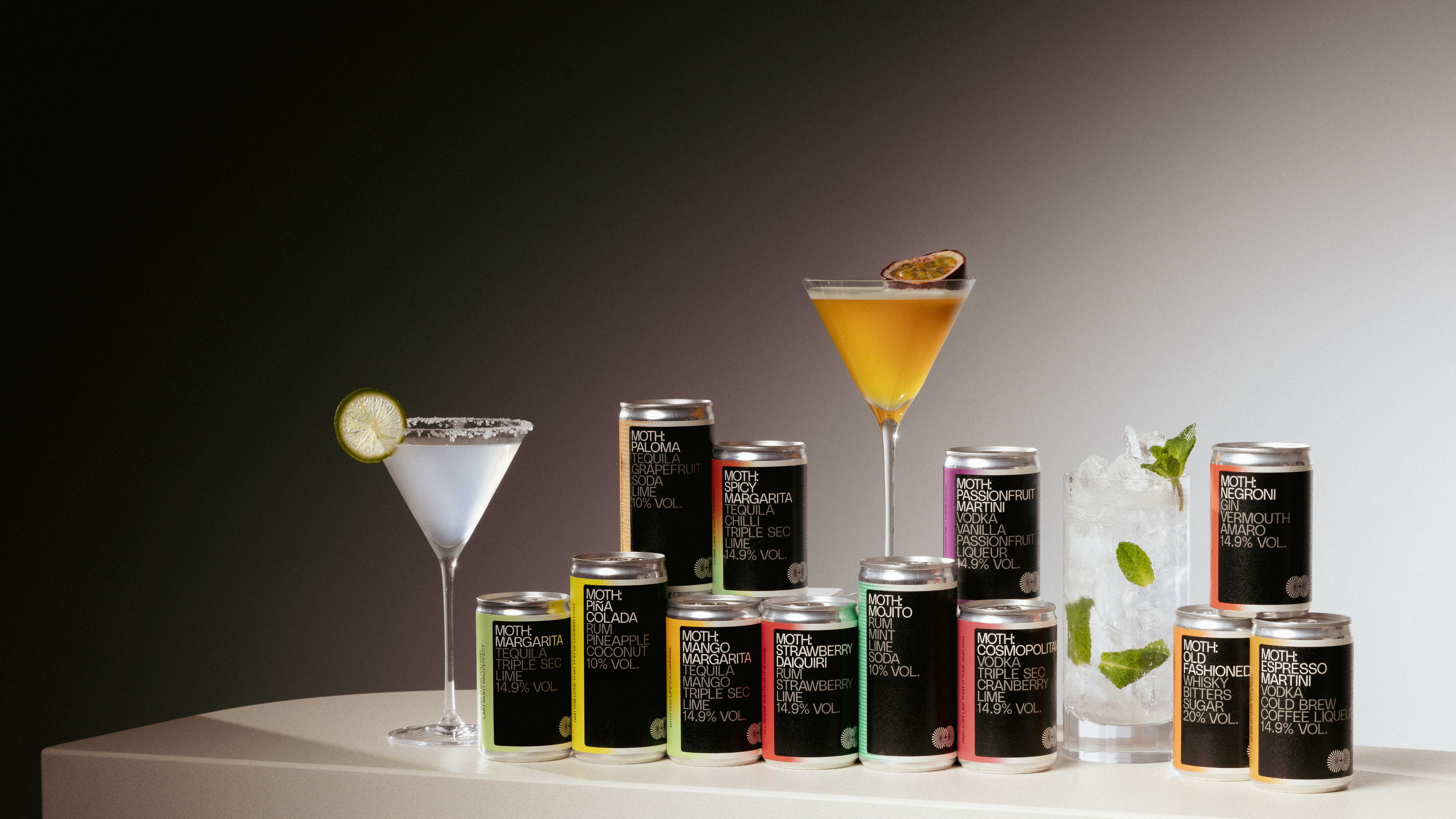 Cans of beverages displayed with cocktails on a table.