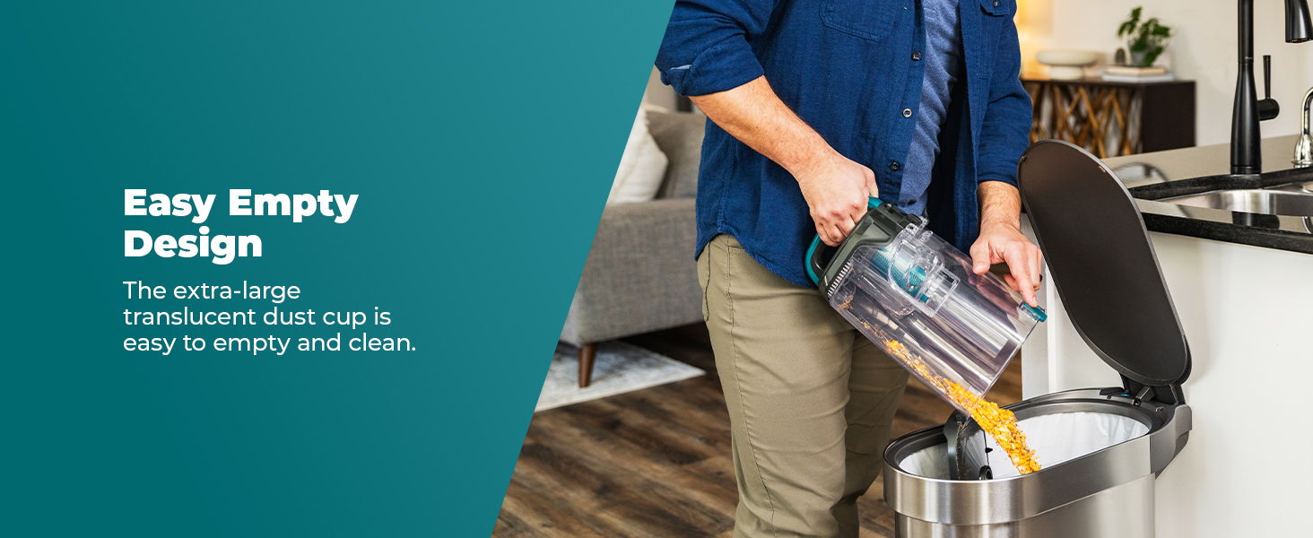 Person emptying a vacuum into a trash can in a modern kitchen.