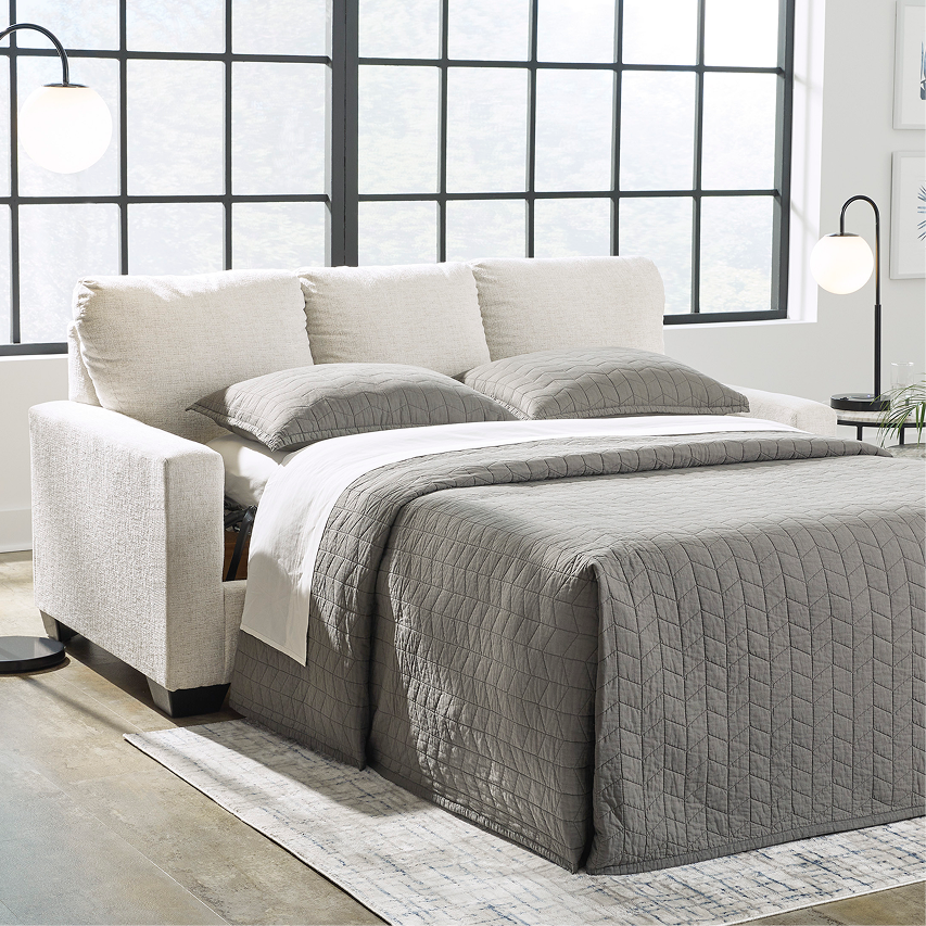 Sleeper sofa styled as a bed with bedding in a bright contemporary room.
