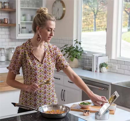 Woman cooking on a Cafe induction cooktop, with a Hestan Cue Smart Pan