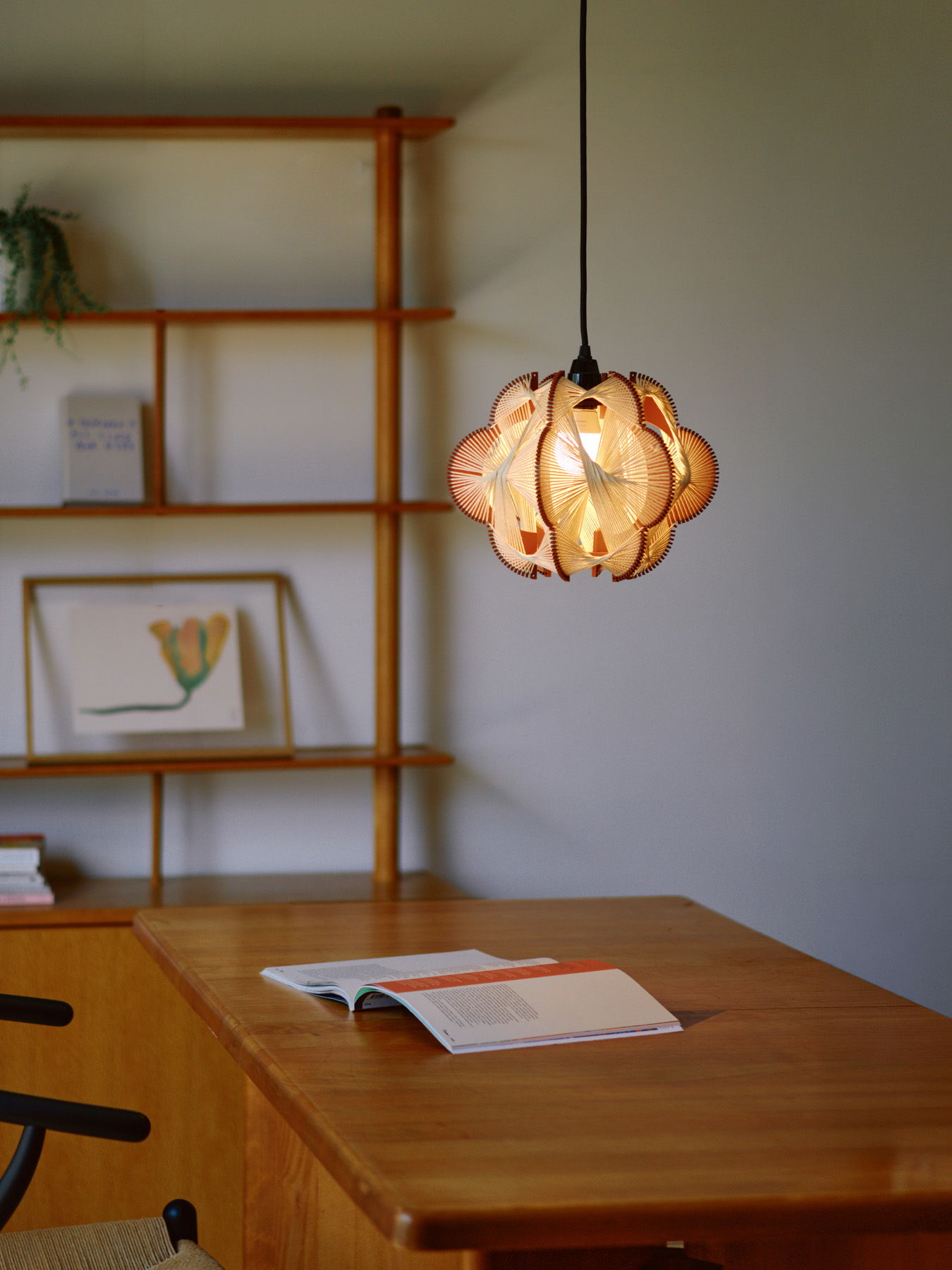 A pendant light hangs above a wooden table with a book.
