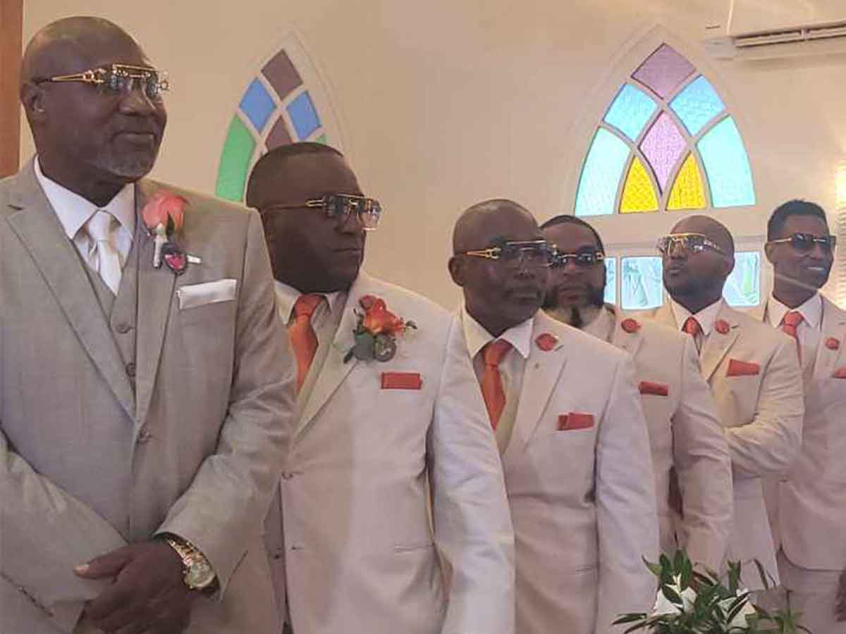 A groom and groomsmen standing at an altar wearing burnt orange accessories