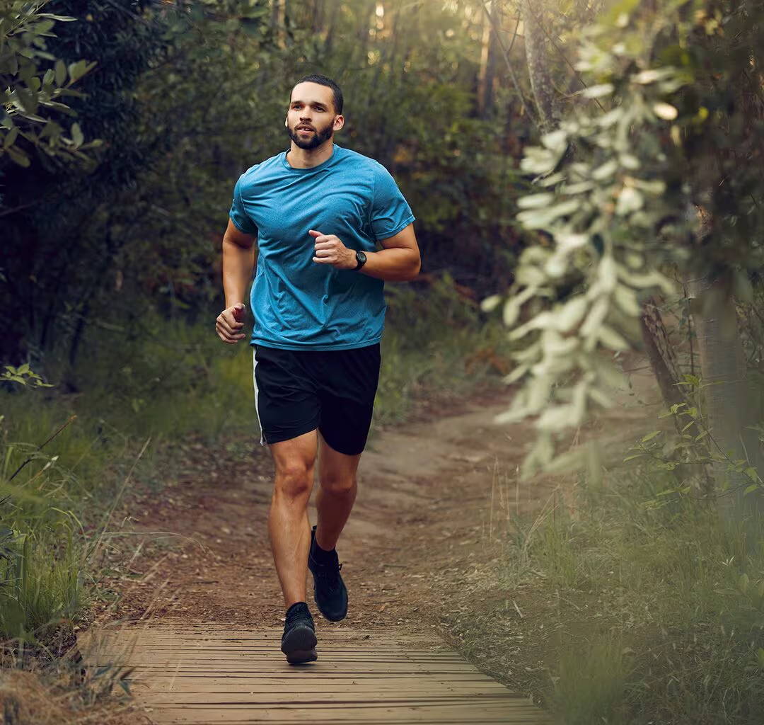 Muž ve sportovních šortkách a tričku si užívá víkendový běh v lese – musí mít svou alergickou rýmu pod kontrolou