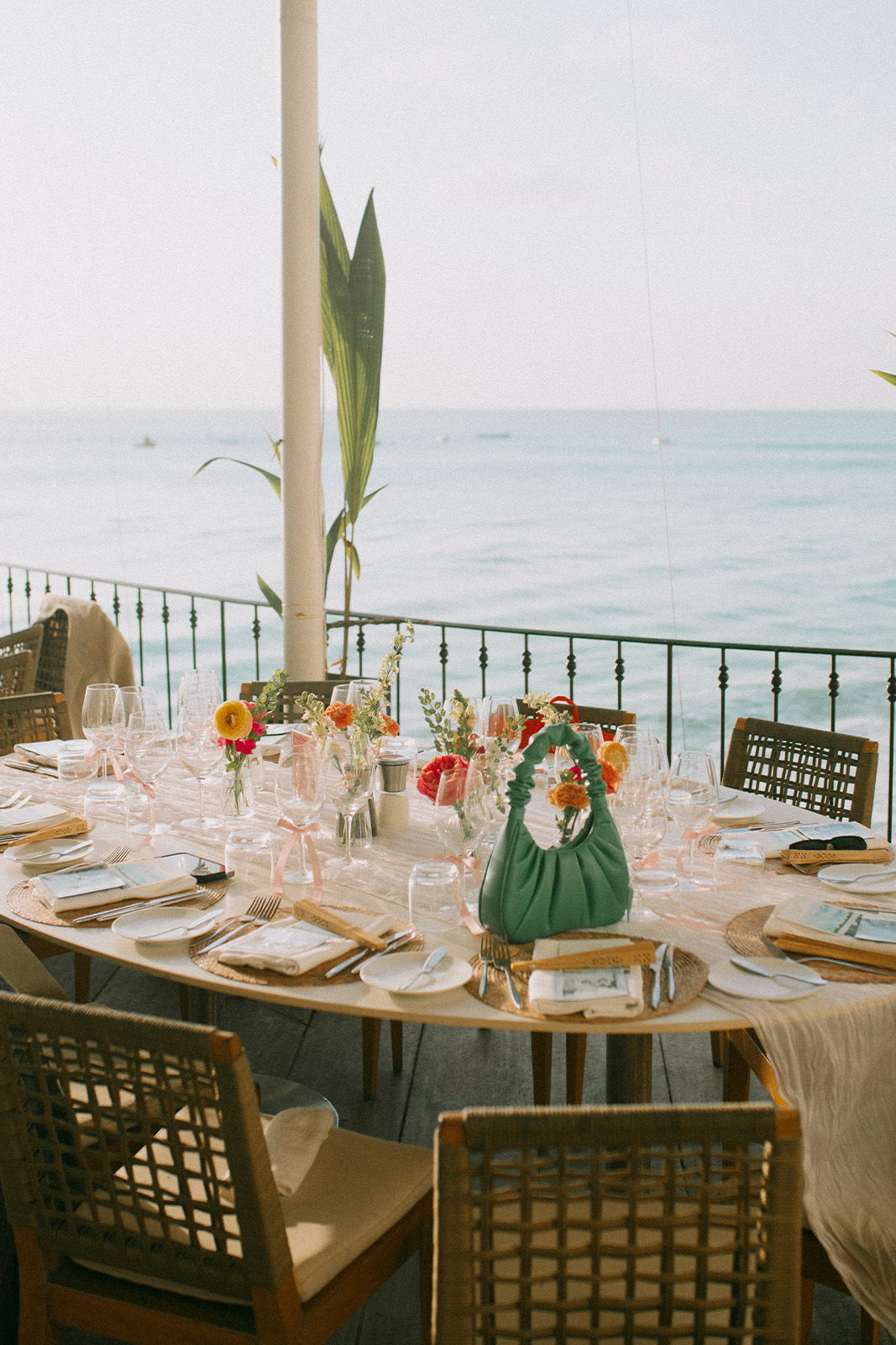A beautifully set dining table by the ocean with flowers and elegant tableware.