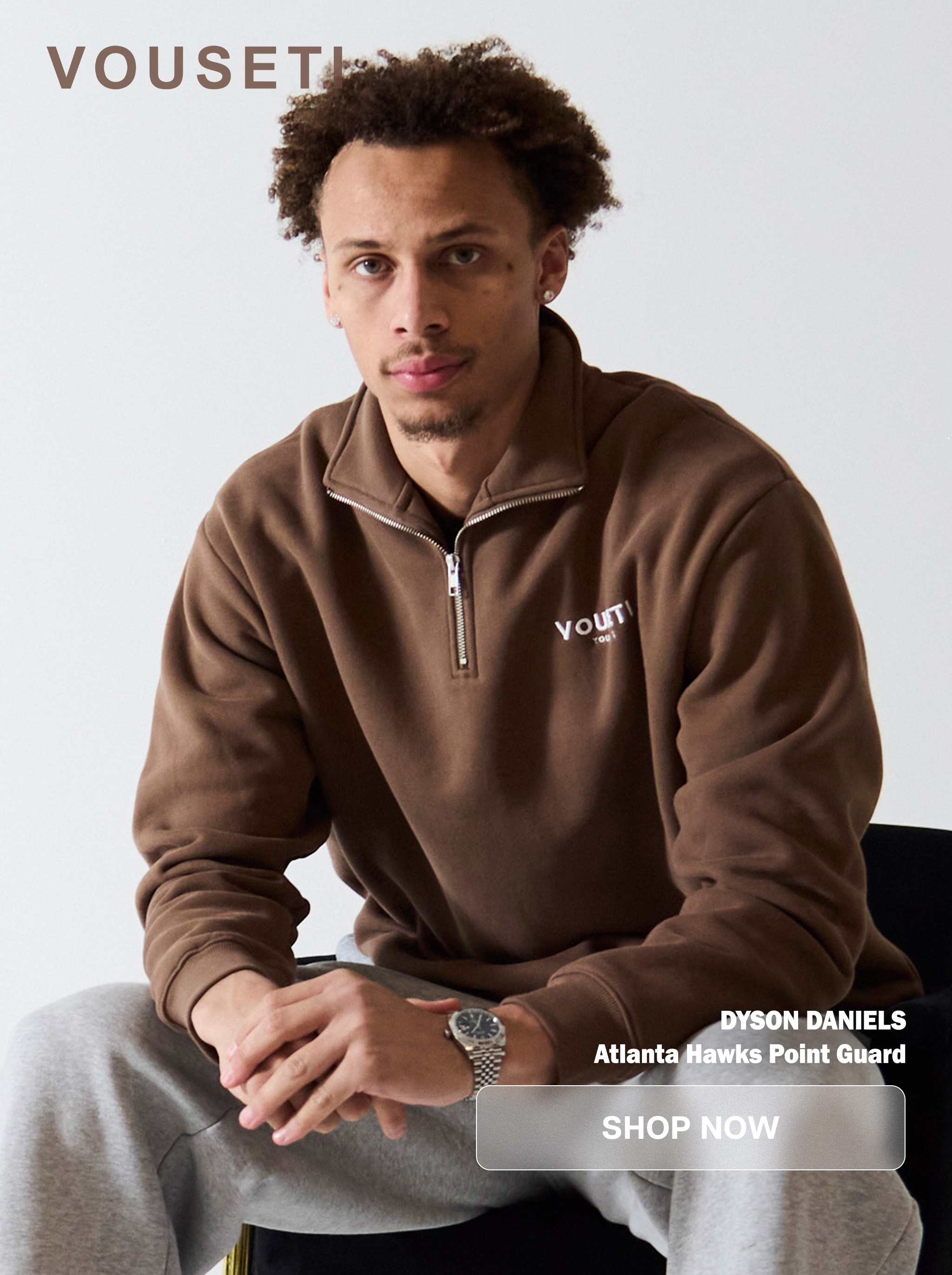 Man in brown zip-up sweater sitting on a chair.