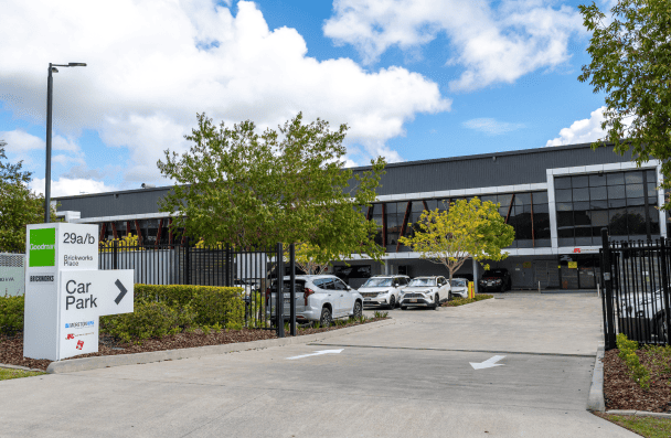 Modern parking facility with cars and signage in a landscaped area.