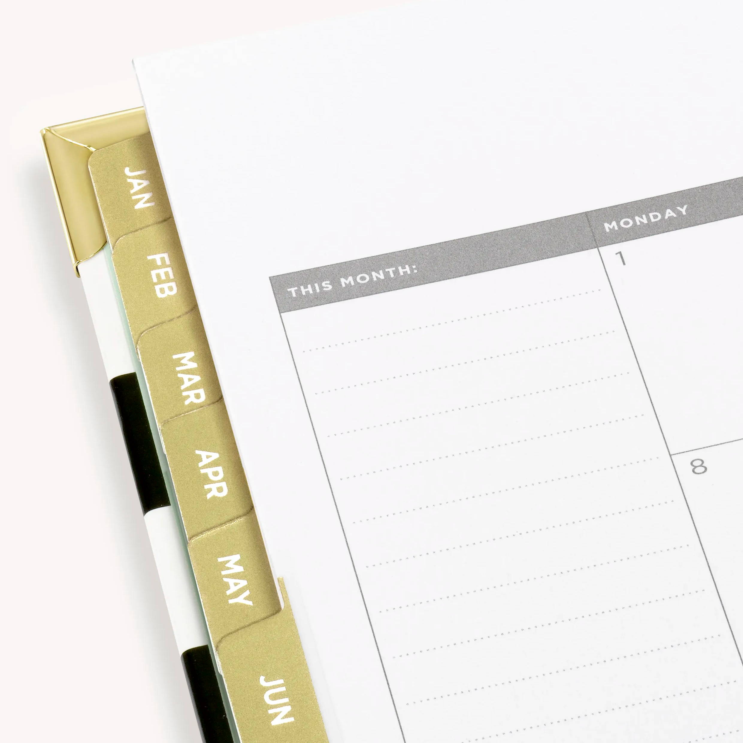 Black and white open planner corner with gold monthly tabs